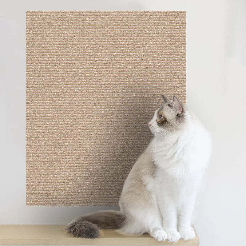 A white and gray cat is sitting on a beige self-adhesive scratching mat designed for furniture protection.