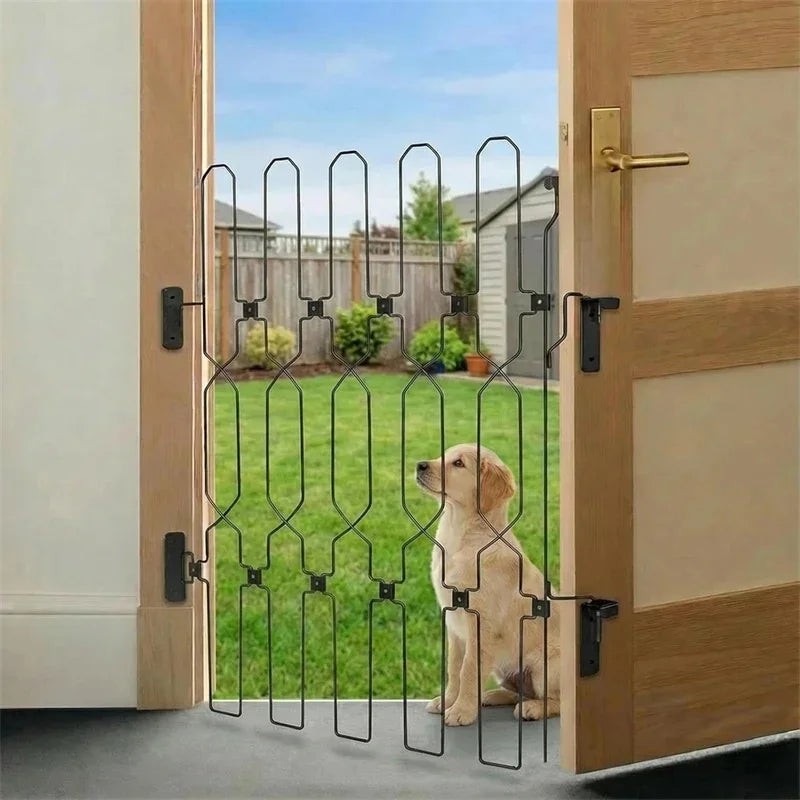 A vertical black metal pet safety gate is installed in a wooden door frame, separating an indoor area from a grassy outdoor y