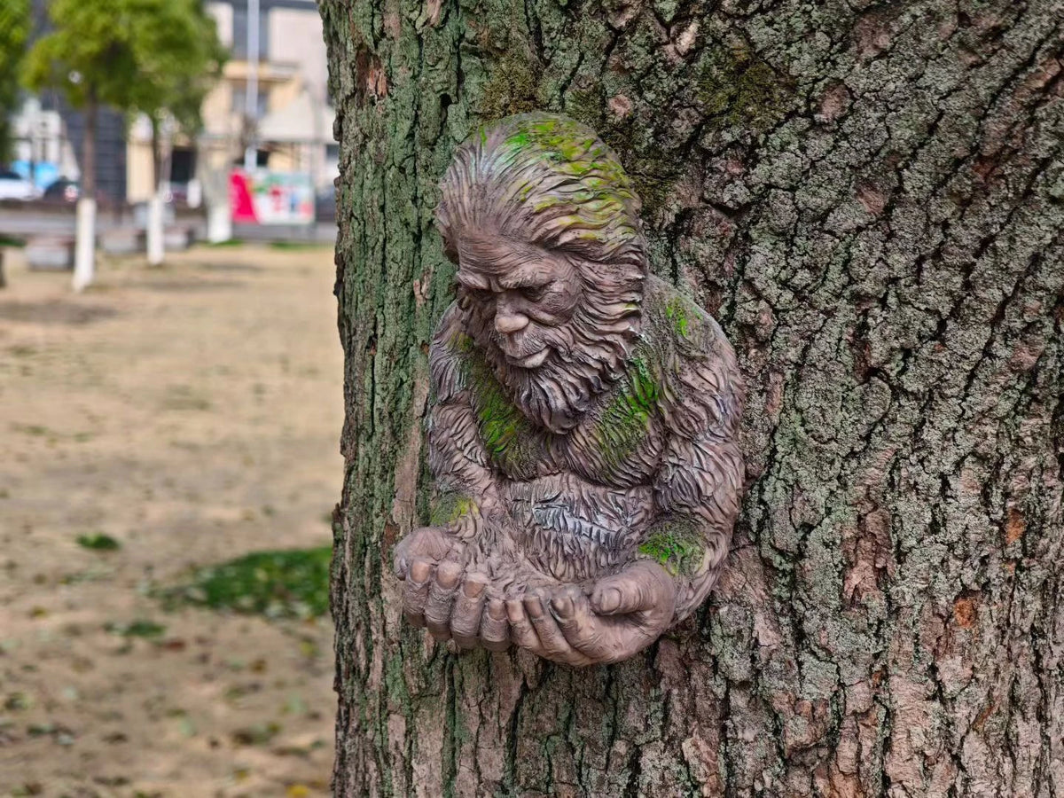A resin sculpture of a monkey hugging its hands carved into the bark of a tree.