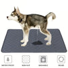 A dog standing on a gray reusable washable pet training mat with icons indicating waterproof, non-slip, washable, and reuse f