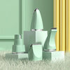A light green pet grooming kit with ceramic blades is displayed on a surface next to yellow curtains.
