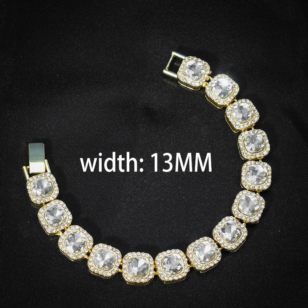 Pulsera de cadena de eslabones cubanos tono dorado con piedras claras y detalles de strass sobre fondo negro.