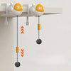 A white and orange automatic lifting cat toy ball is suspended from a shelf, with a yellow marker dangling below it.