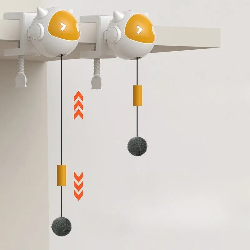 A white and orange automatic lifting cat toy ball is suspended from a shelf, with a yellow marker dangling below it.