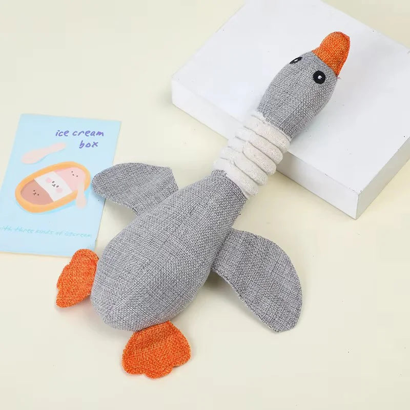 A gray plush toy shaped like a penguin with orange feet and a white collar, designed as a squeaky dog toy.