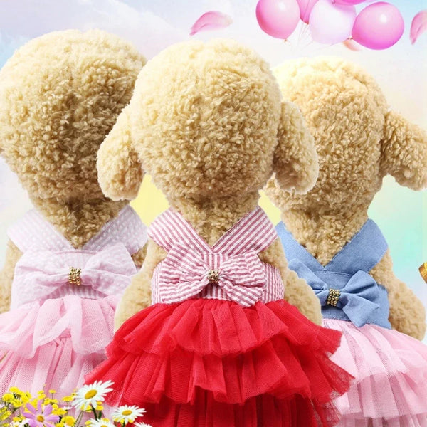 Three fluffy dog plush toys wearing pink and red ruffled mesh skirts