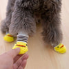 A hand is holding a yellow anti-slip pet sock designed for dog and cat protection.