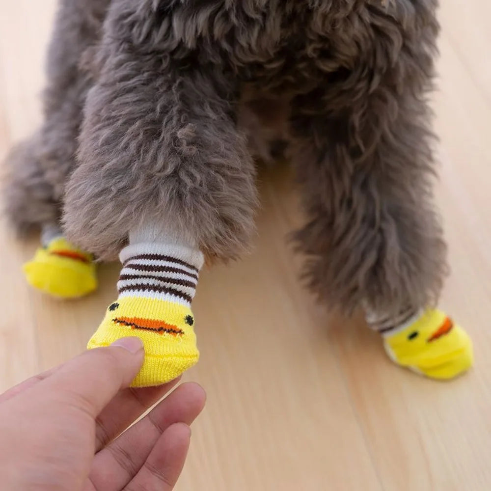 A hand is holding a yellow anti-slip pet sock designed for dog and cat protection.