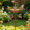 Bañera para pájaros de bronce vintage montada en soporte, con almohadillas para los pies de las aves, en un jardín exuberante