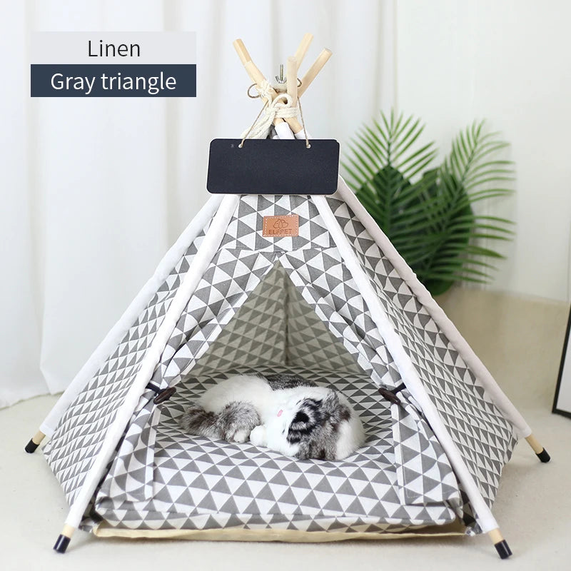 A gray triangle linen teepee pet tent with a removable cushion and blackboard, featuring a white fluffy pet inside.