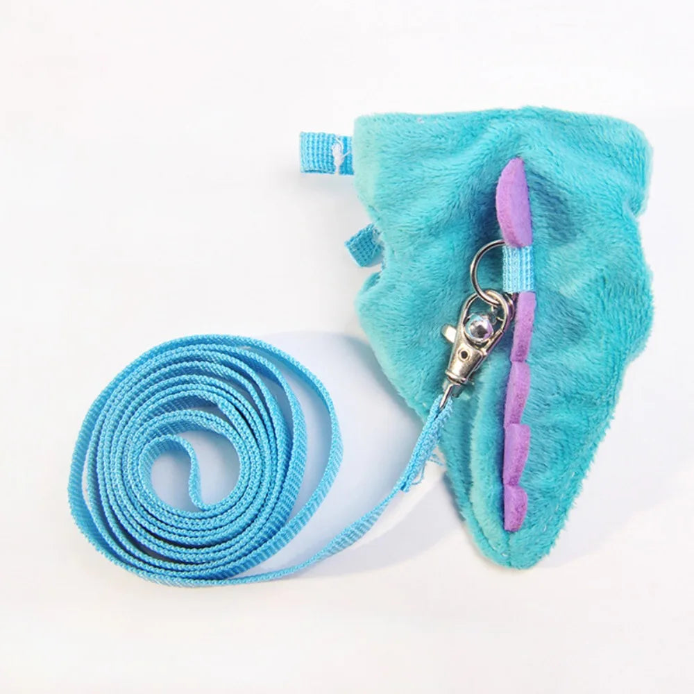 A teal fuzzy vest harness with purple trim and a silver clip is shown next to a coiled blue leash.