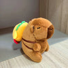 A brown capybara plush doll wearing a brown harness and featuring yellow wings.