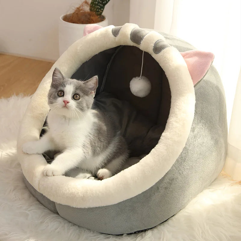A fluffy gray and white kitten is relaxing inside a cozy, round pet tent bed with soft lining.