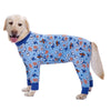 A light-colored dog wearing a blue jumpsuit with an orange and white cartoon animal print.