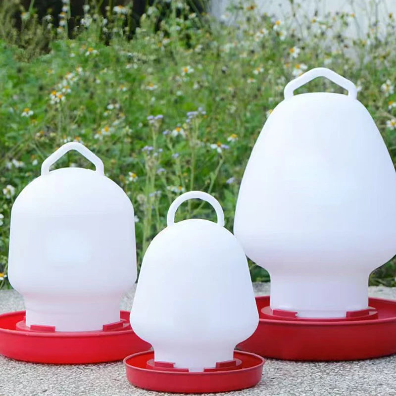 Three white automatic poultry feeder and waterer units sitting on a gray surface.