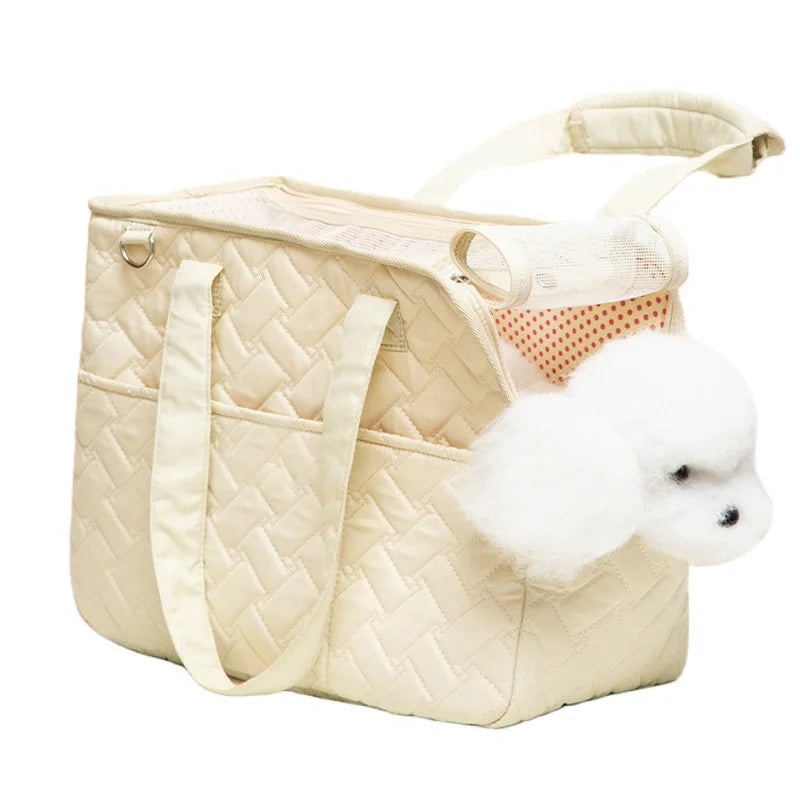 A beige quilted portable pet carrier bag with light beige handles and a white fluffy toy inside.