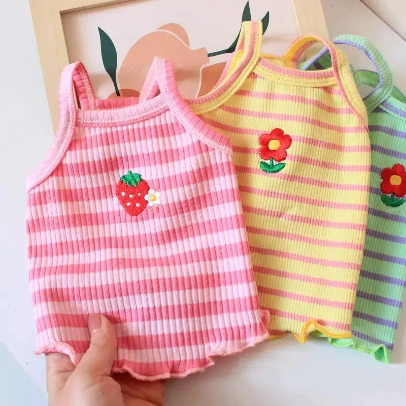 Pink striped dog vest with a red strawberry print and a yellow striped vest.