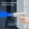 A hand holds a white electric nano steam disinfecting spray gun emitting a blue mist in a home setting.
