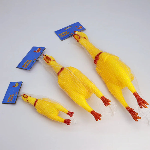 A yellow squeaky rubber chicken dog toy is shown with its packaging and a blue label.
