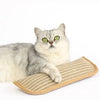 A fluffy gray and white cat is resting on a beige, textured cat scratcher mat.