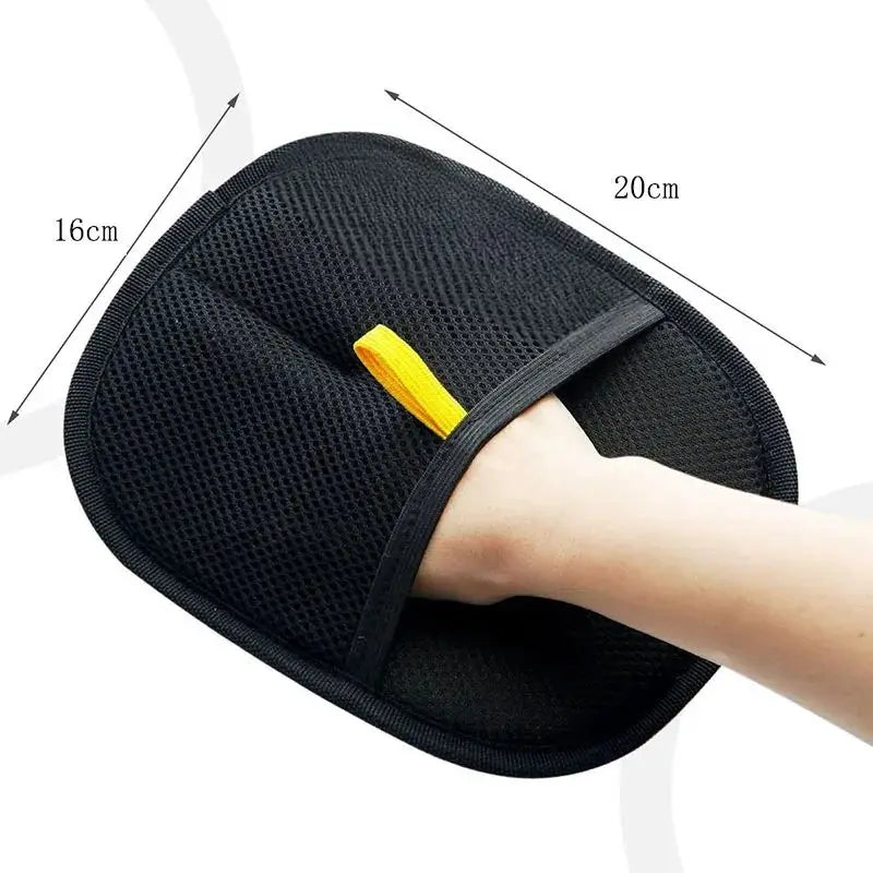 Black reusable pet hair removal glove being worn on a hand, showing its size and function.