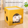 A yellow cardboard cat scratching box with an entrance for a white cat.