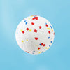 A white chew ball speckled with small red, blue, and yellow pieces against a light blue background.