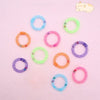 A collection of colorful, soft mesh donut chew toys in various colors like blue, green, orange, and purple are scattered on a