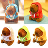Three plush capybara dolls wearing hooded outfits in pink, green, and yellow.