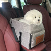 Ein flauschiger weißer Hund ruht in einem grauen Transportbehälter auf dem Auto-Sitz.