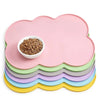 A stack of pink, green, and purple non-slip pet mats with a bowl of kibble on top