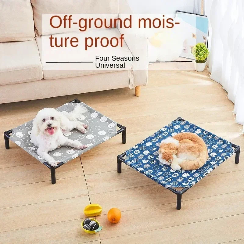 A portable folding pet bed with a blue patterned cover is shown on a wooden floor next to a sofa.