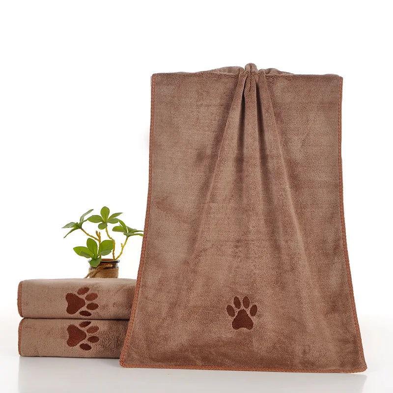 Une serviette pour animaux en microfibre brune et ultra-absorbante, à côté d'une petite plante en pot.