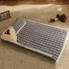 A gray orthopedic memory foam dog bed with a tan accent and a brown stuffed toy resting on a cream carpet.
