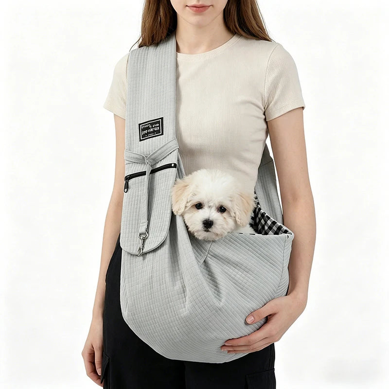A woman is holding a light gray crossbody pet carrier bag for dogs and cats.