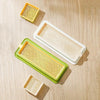 A set of layered cat grass growing trays in yellow and green plastic.