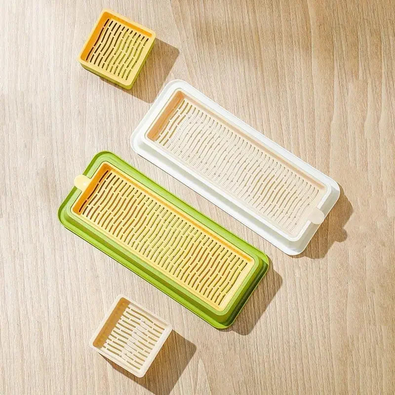 A set of layered cat grass growing trays in yellow and green plastic.
