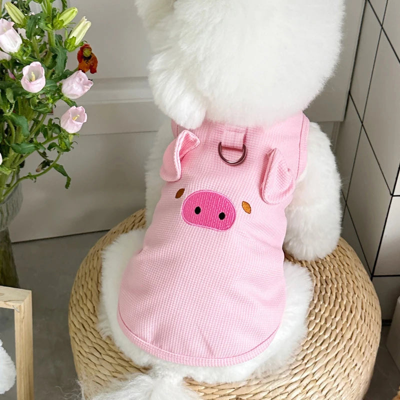 A pink waffle knit pet vest for a dog is displayed on a woven surface.