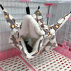 A cozy fleece double layer hammock bed for hamsters is shown inside a wire cage.