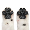 A pair of black anti-slip paw grips with a textured pattern are shown on a white dog paw.
