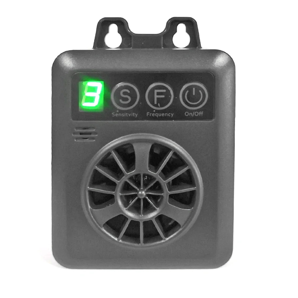 A gray electronic device with a green light and a circular grille for an ultrasonic anti-barking dog repellent.