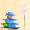 A blue interactive cat turntable toy with rolling balls and a pink feather wand on a light background.