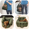 A brown dog is resting inside a green durable pet car seat with safety straps.