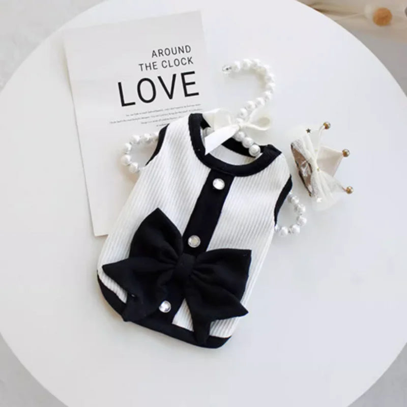 A black and white striped pet dress for a small dog with a bow detail, displayed on a white surface.