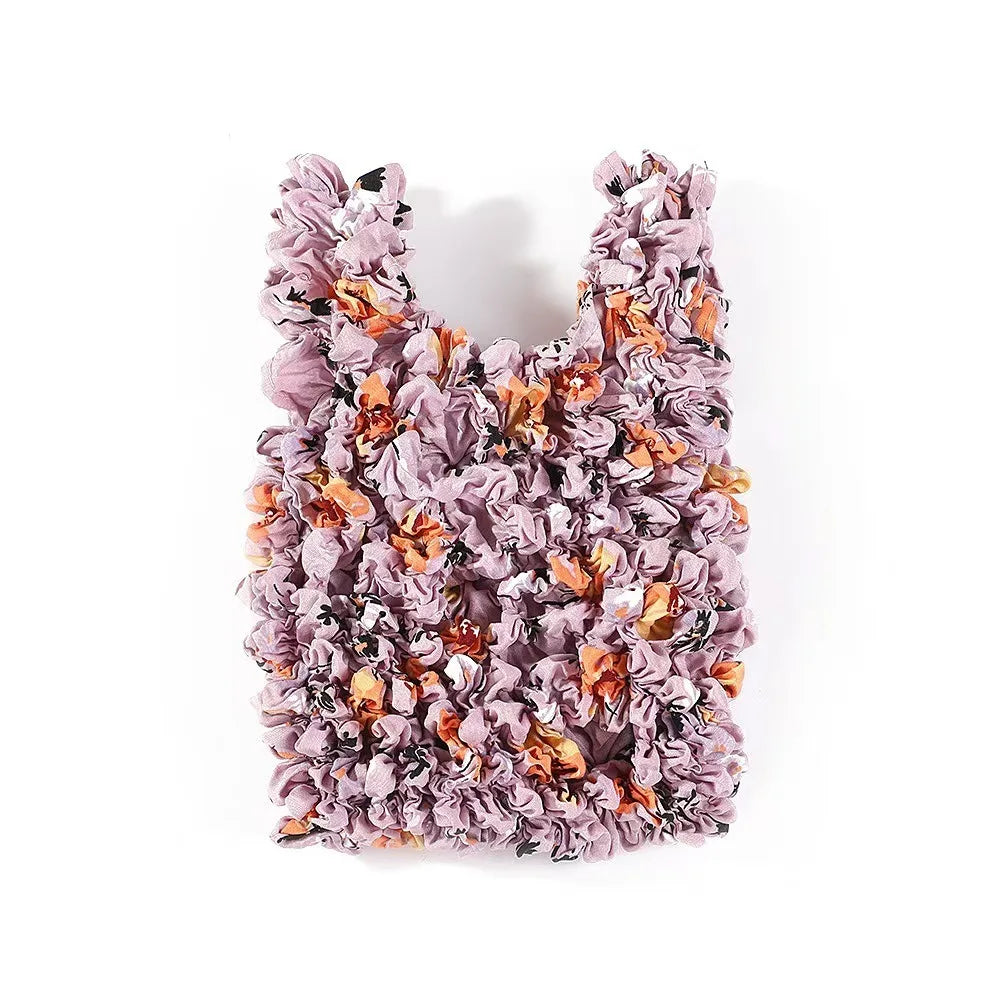 A reusable foldable bubble shopping bag made of ruffled fabric in shades of purple and orange.
