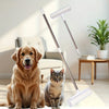 A golden retriever and a tabby cat sit next to a silver retractable lint roller mop with a white handle and clear cleaning pa