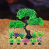 Un árbol artificial en miniatura y plantas coloridas exhibidos en arena para decoración del hogar.