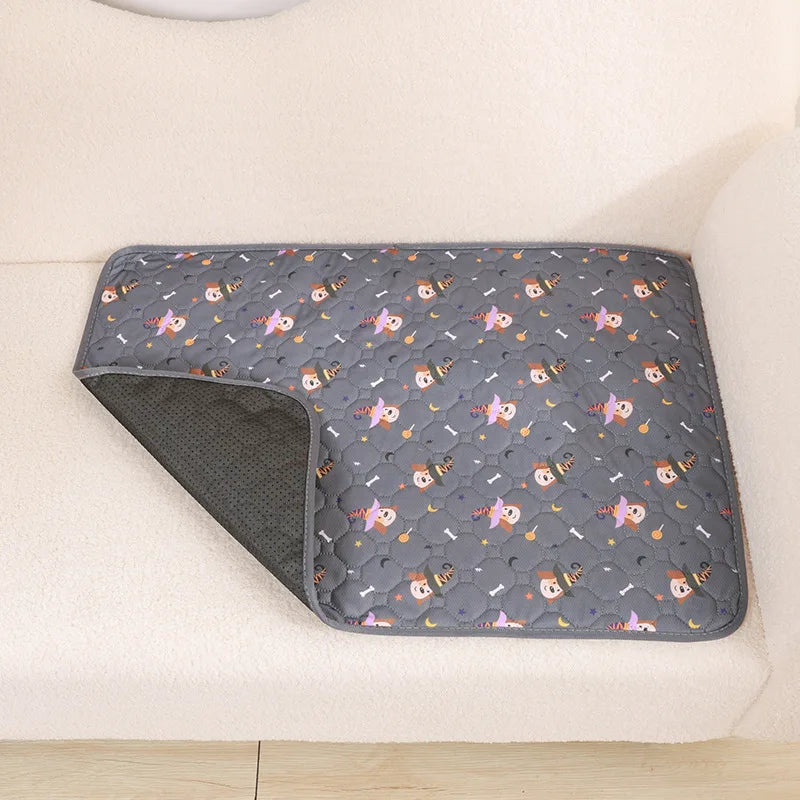 A gray pet training mat with a repeating pattern of small animal figures is placed on a light-colored surface.