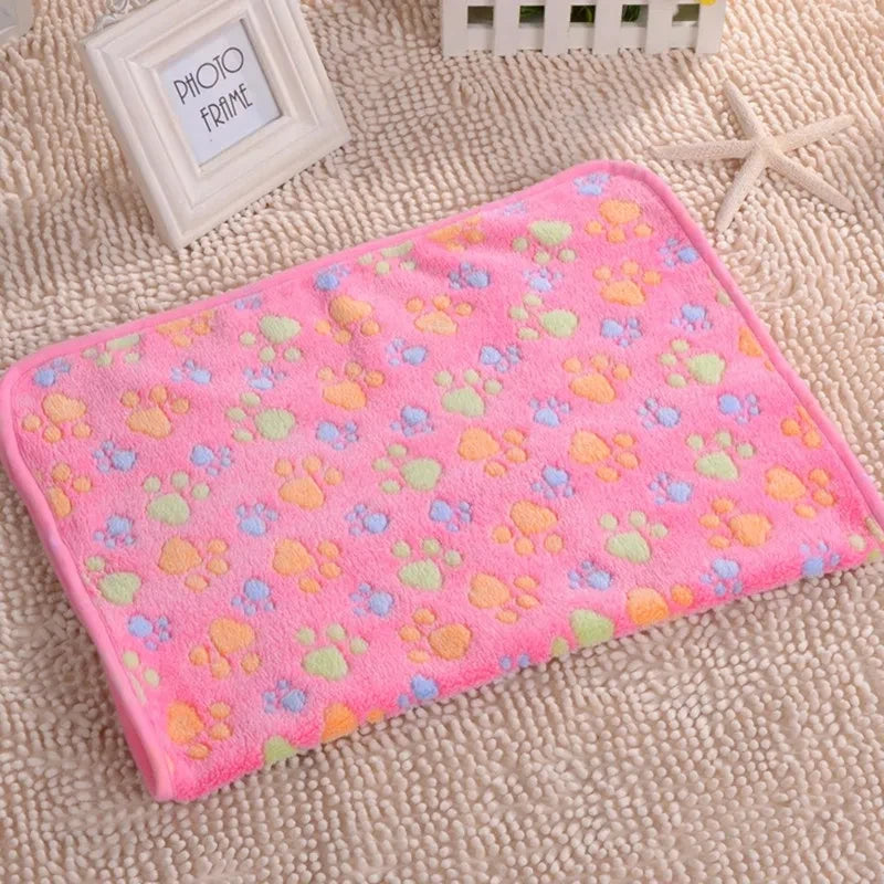 Pink fleece pet bed mat cover with scattered orange and light green paw prints on a beige fabric background.