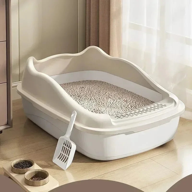 A white high-sided cat litter box with an anti-splash design is shown on a wooden floor next to a small scoop.